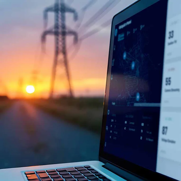 Tablero de red eléctrica de UbiVu frente a una línea de transmisión al atardecer